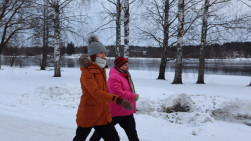 Liikunnanohjaaja ja asiakas kävelyllä Vuoksen varrella talvella.