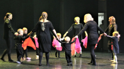 Children and adults dance in a circle