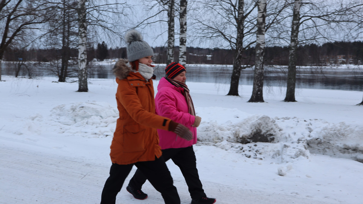 Kaksi henkilöä talvella kävelyllä Vuoksen varrella.