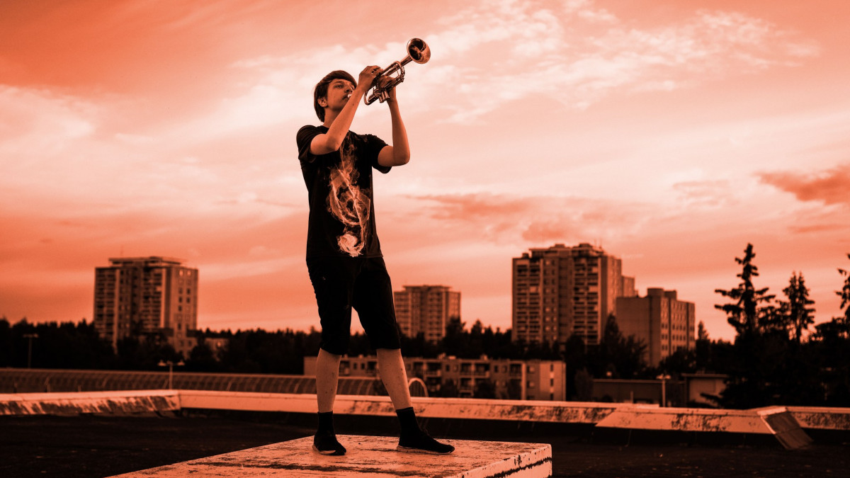 horn player on the roof, apartment buildings in the background.
