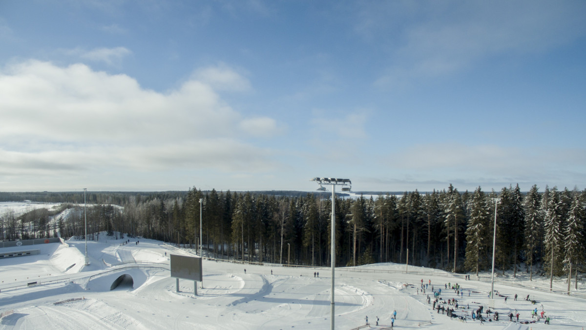 Ilmakuva Ukonniemi-stadionilta talvella. Etuosassa latuja, taustalla metsää ja sininen, aurinkoinen taivas.