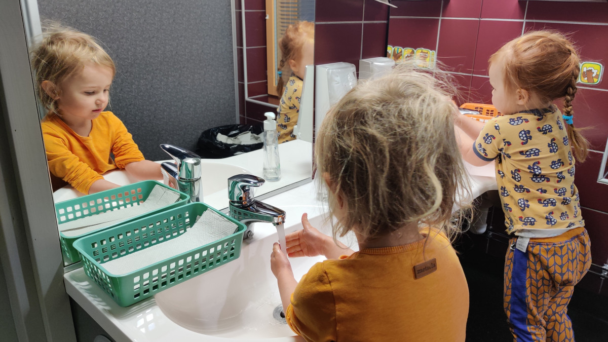 Kaksi pientä tyttöä pesemäsä käsiä.