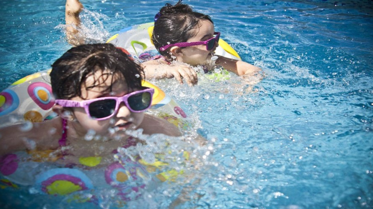 Two children swimming in swimming goggles.