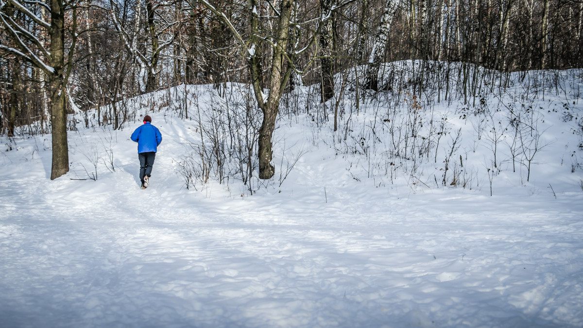 Mies juoksee talvisessa maisemassa.