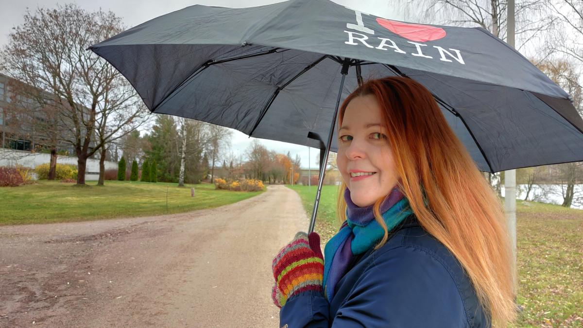 Kati Bragge kävelee sateenvarjon kanssa.