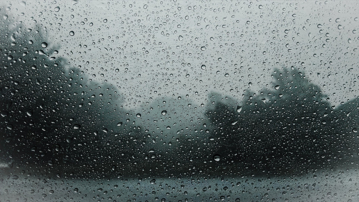 Sadepisaroita ikkunassa, ulkona sateista ja sumuista.