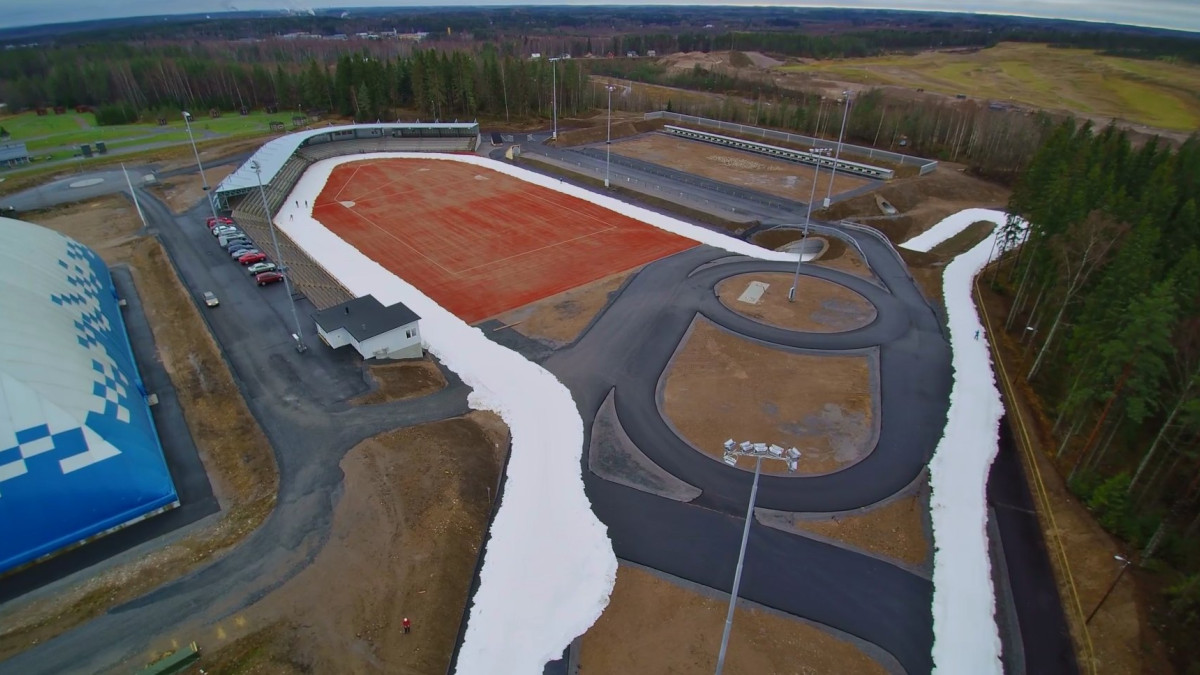 an aerial view of the track going around a snow-free stadium.