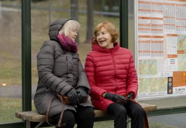 Two old women sitting at a bus stop.