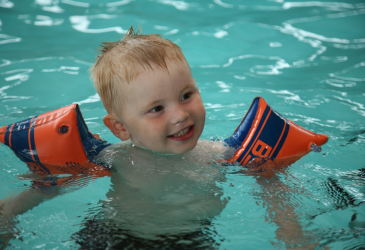 Child with floats in swimming pool.