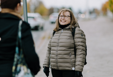 A woman stands on the street and smiles.