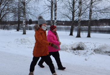 Kaksi henkilöä talvella kävelyllä Vuoksen varrella.