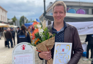 Heikki Pöyhia has flowers and an award certificate in his hands.