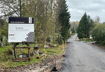 On the edge of the street in a gravel-surfaced residential area, a construction site sign in Imatra.