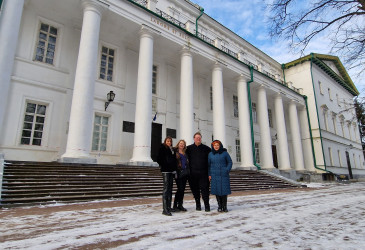 Четыре человека стоят перед классическим зданием.