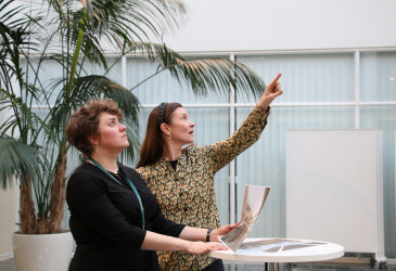 Ilona Tuomi ja Laura Kokki seisovat Imatran kaupungintalon aulassa ja esittelevät Erä- ja luontokulttuurimuseon suunnitelmia.