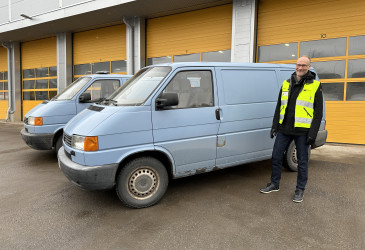Markku Puuska, CEO von Imatran Kipa, und zwei blaue Lieferwagen auf dem Weg nach Nischyn vor der Halle mit der gelben Tür.