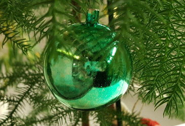 Vihreä joulupallo roikkuu kuusen oksassa.