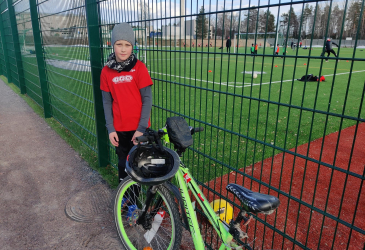 A boy and a bicycle on the side of a soccer field.