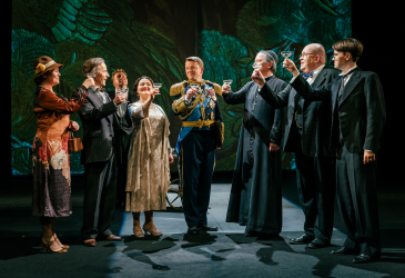 Kuninkaan puhe -näytelmän näyttelijät skoolaavat lavalla. Asut 1930-luvun, käsissä shampanjalasit.
