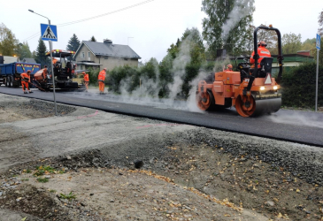 Työkoneet tekemässä uutta asfalttia asuinalueella.