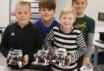 Pojat hymyilevät lego-robotit käsissään