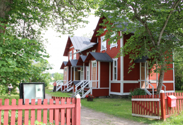 Teollisuustyöväen asuntomuseon punainen puinen rakennus puiden siimeksessä. 