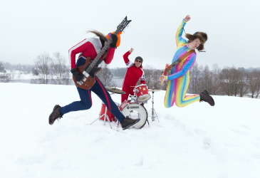 Three band members playing outside and jumping
