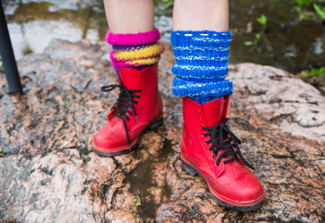 Feet, in red shoes and woolen socks standing on a stone in summer.