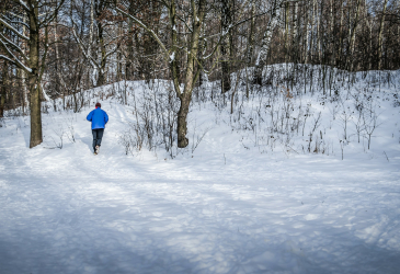 Mies juoksee talvisessa maisemassa.