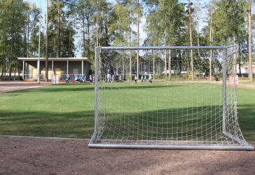 A soccer goal, a sports field and playing children.