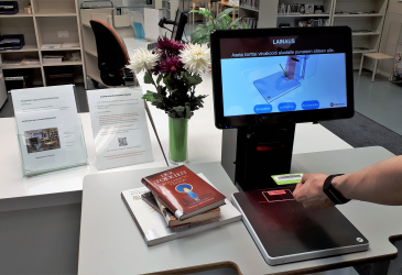 A customer self-borrowing with the library's loan machine.