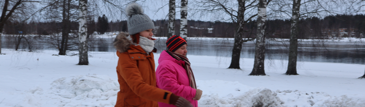 Liikunnanohjaaja ja asiakas kävelyllä Vuoksen varrella talvella.