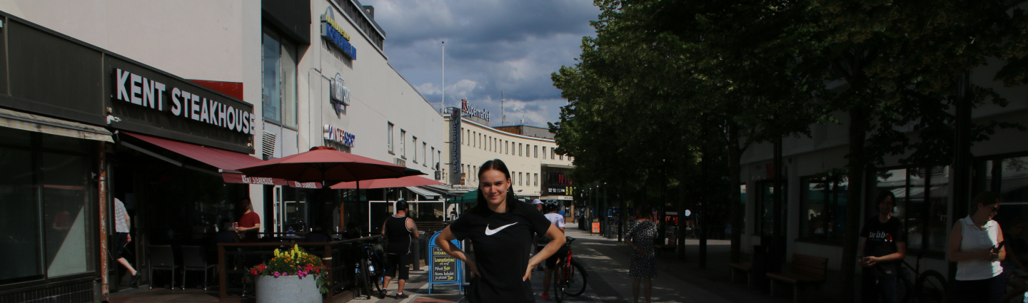 Salminen stands behind the pride flag he painted, with a pedestrian street in the background.