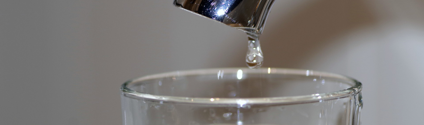 A drop of water falls into a glass of water.