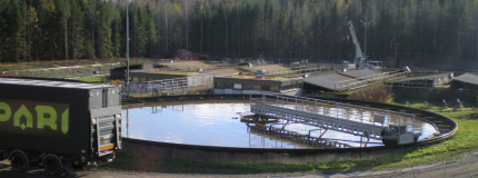The pool of the cleaning plant, with a dirt road in front and a forest behind